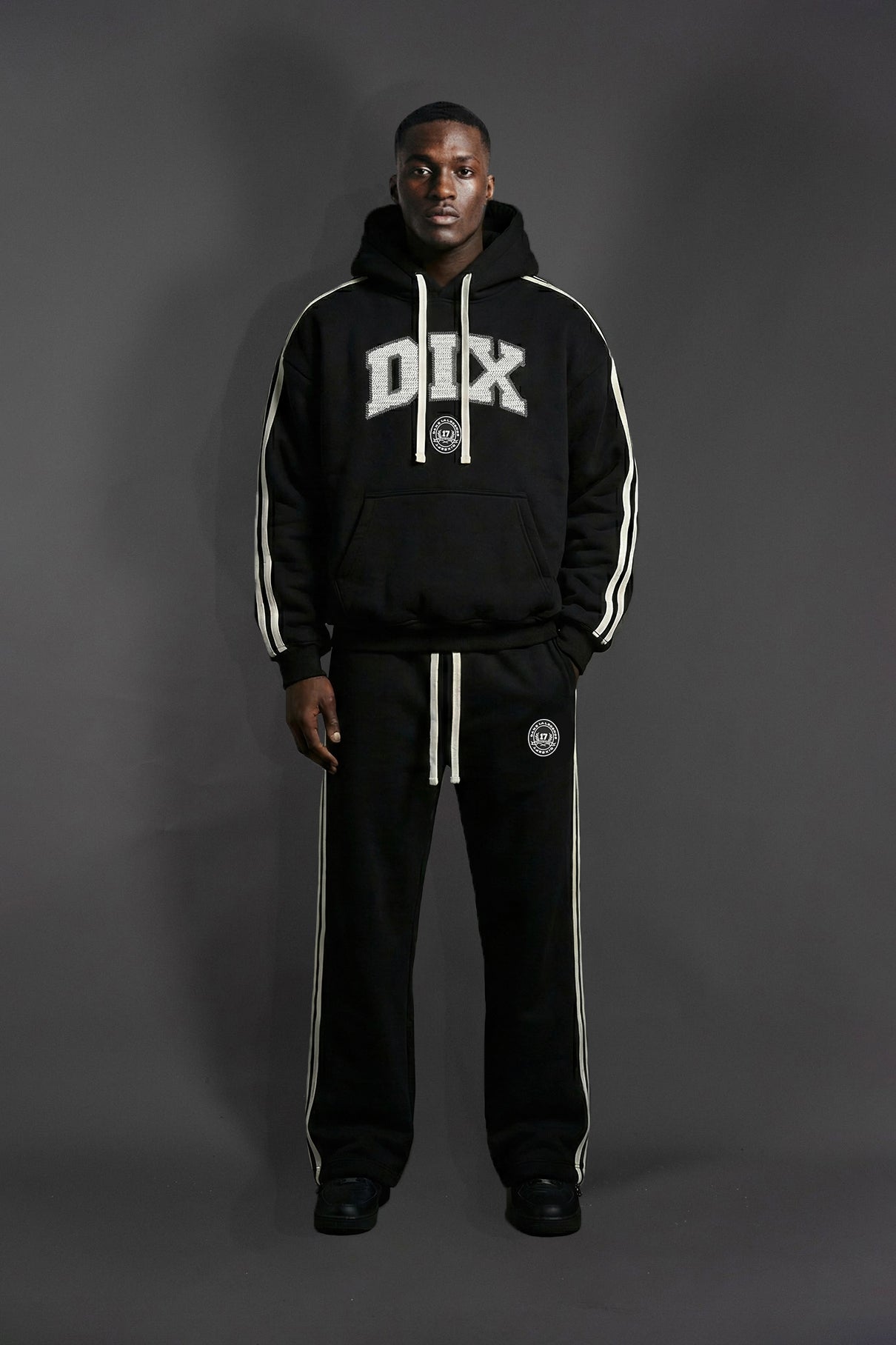 Person wearing a black tracksuit with 'DIX' branding on a gray background