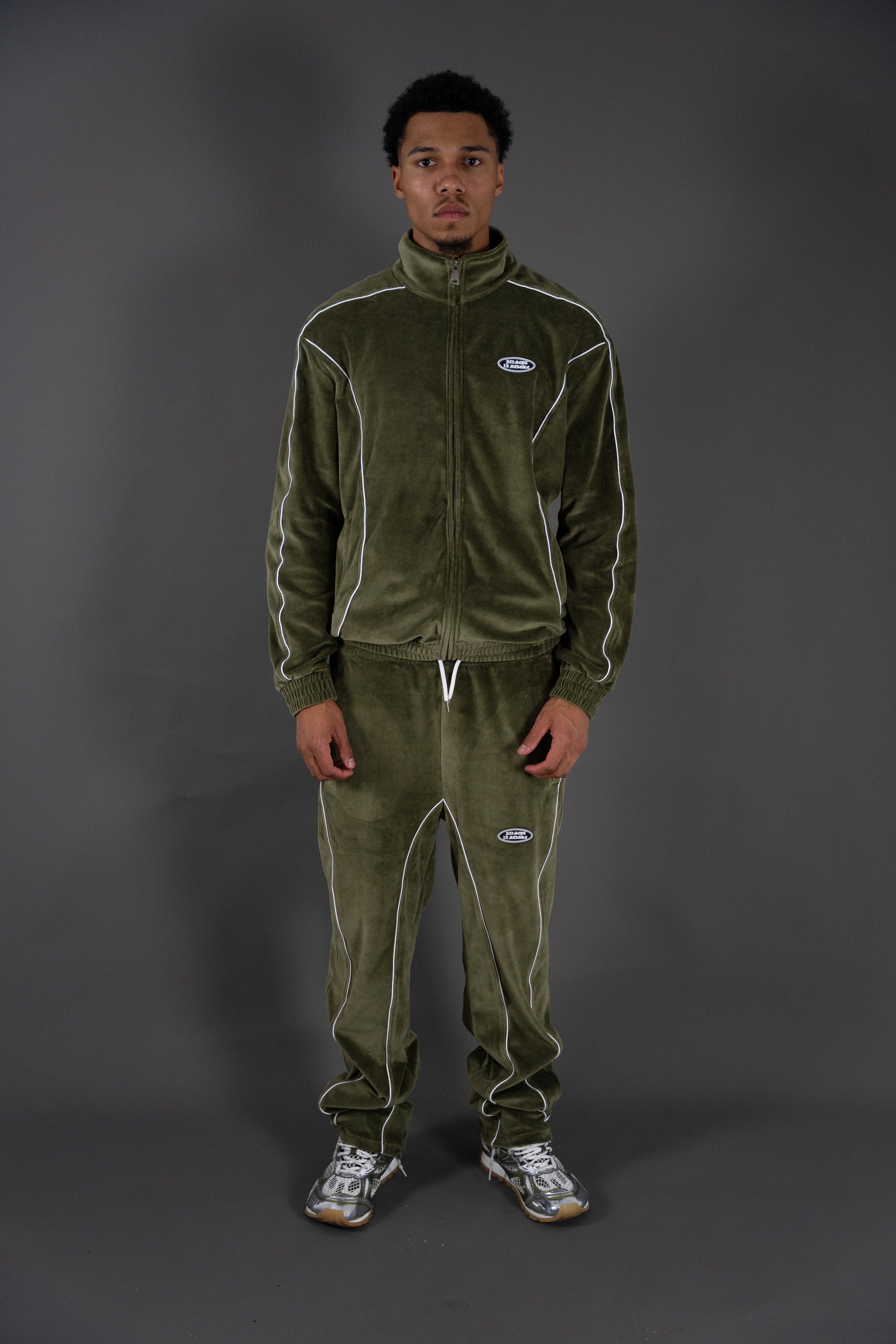 Person wearing a green tracksuit with a logo on a gray background
